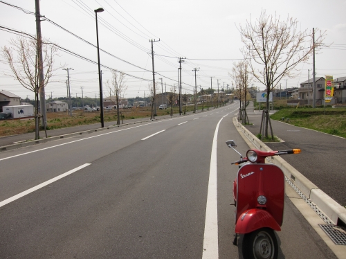 中古車仕上げ中のベスパと新興住宅地の道