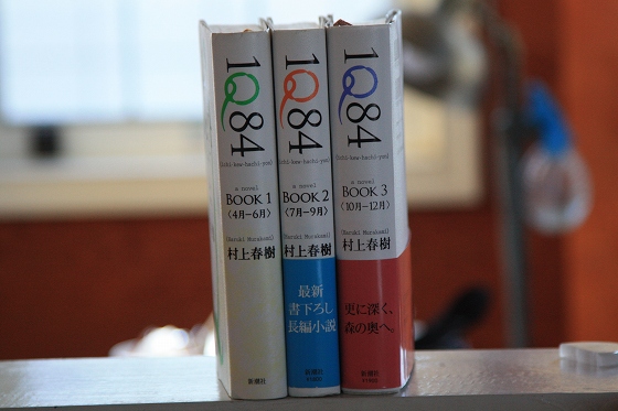 机の上に置かれた村上春樹の小説『1Q84』とお酒。