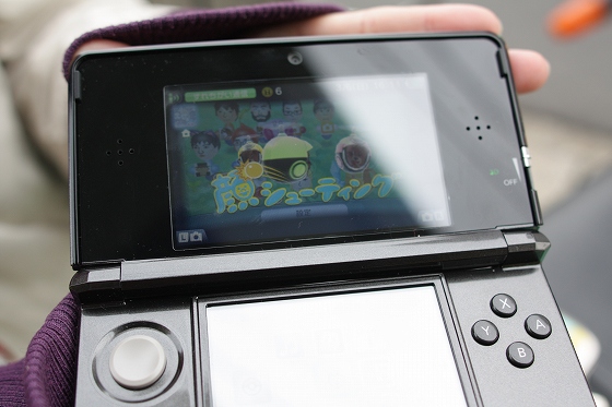 任天堂3DSを持つ手元、3D画面が開いた状態