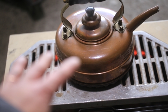 ストーブで手を温めながら作業する様子