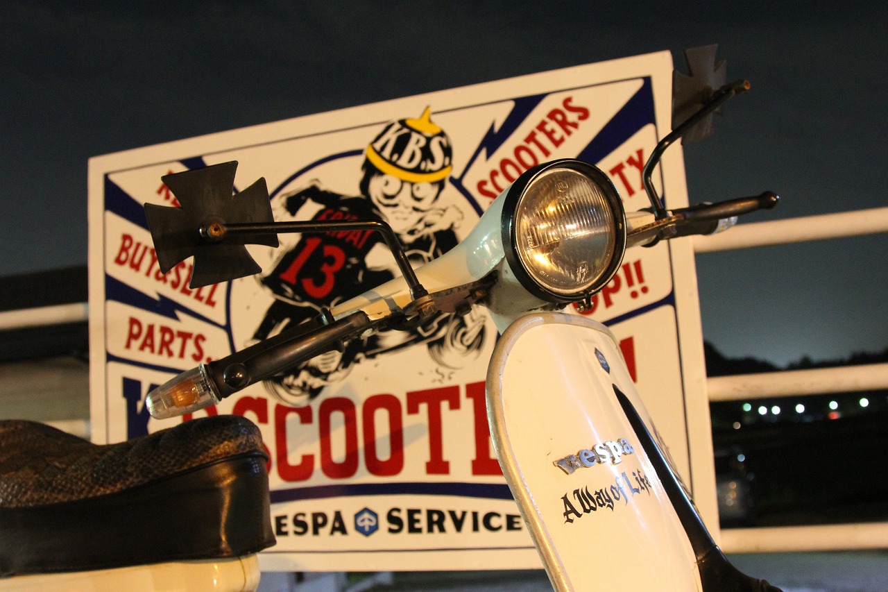 K.B.SCOOTERSの看板と夜のベスパフロントまわりのアップ