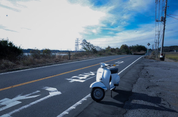 郊外の道路に停められた白いベスパ125ET3