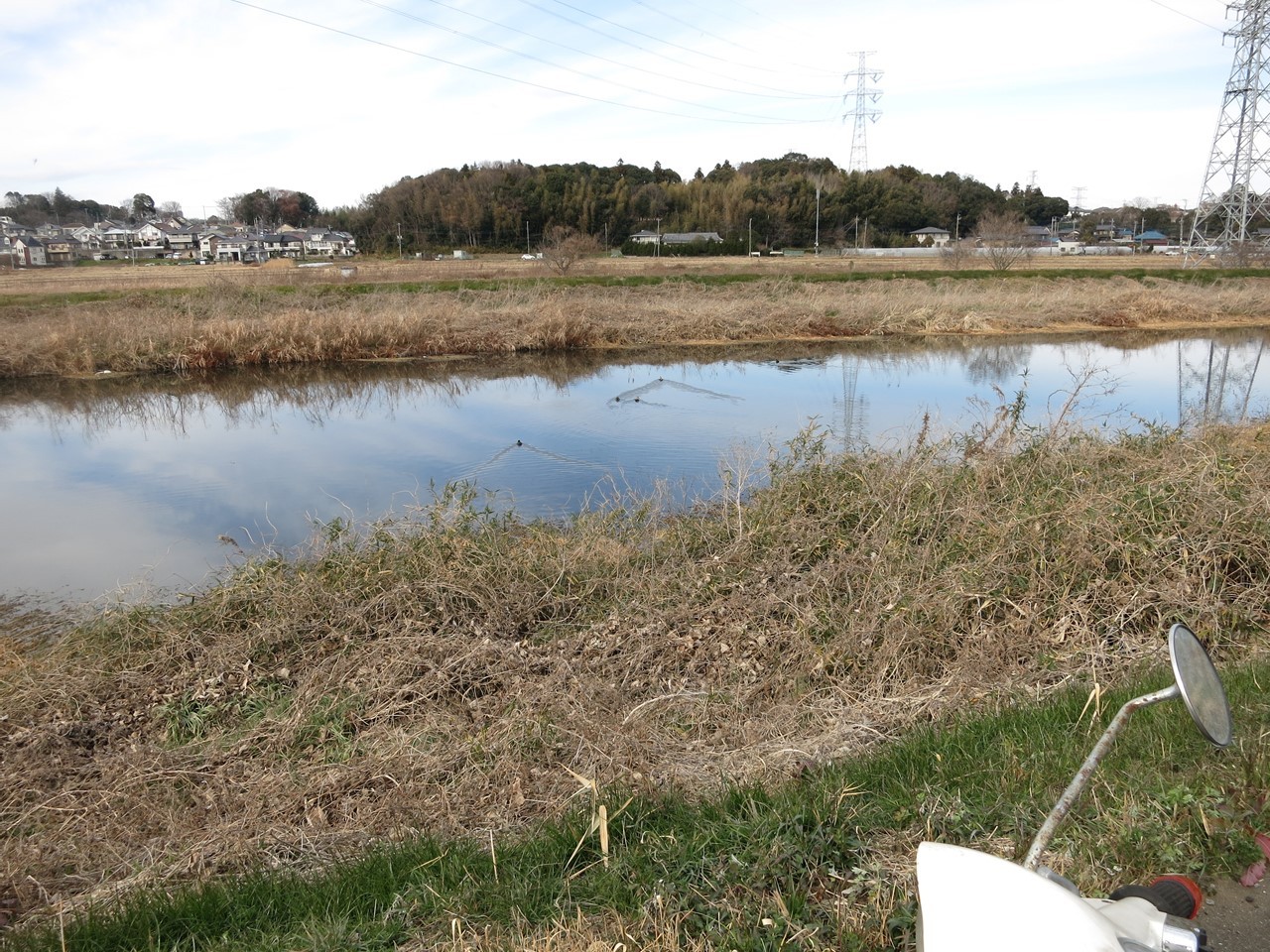 ベスパを押しながら川沿いを歩く様子