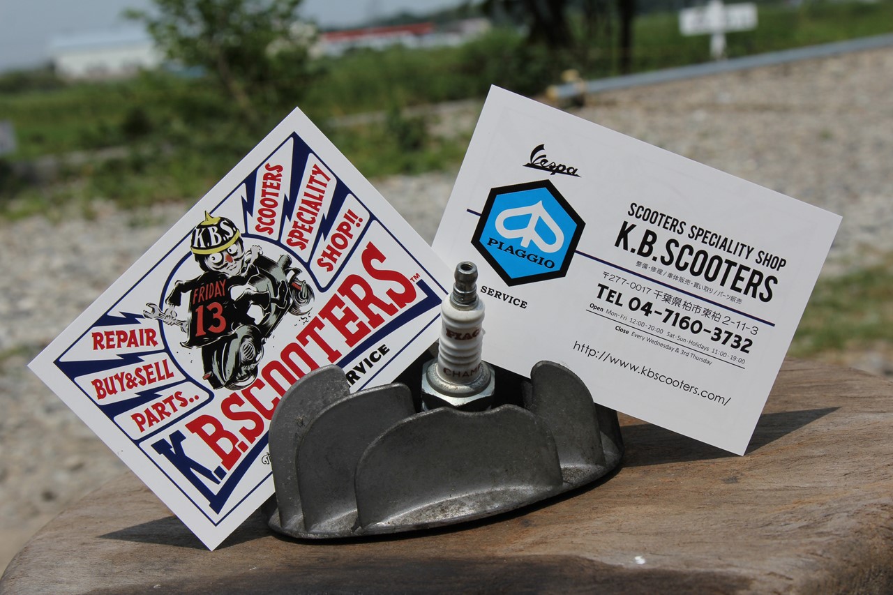 店舗前に設置されたK.B.SCOOTERSの看板と黄色いベスパ