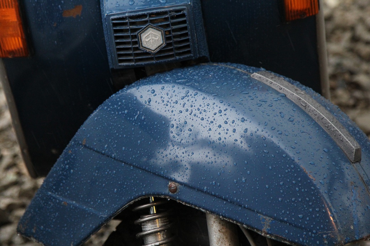 ワックスが効いたベスパの車体に水滴が転がるクローズアップ。