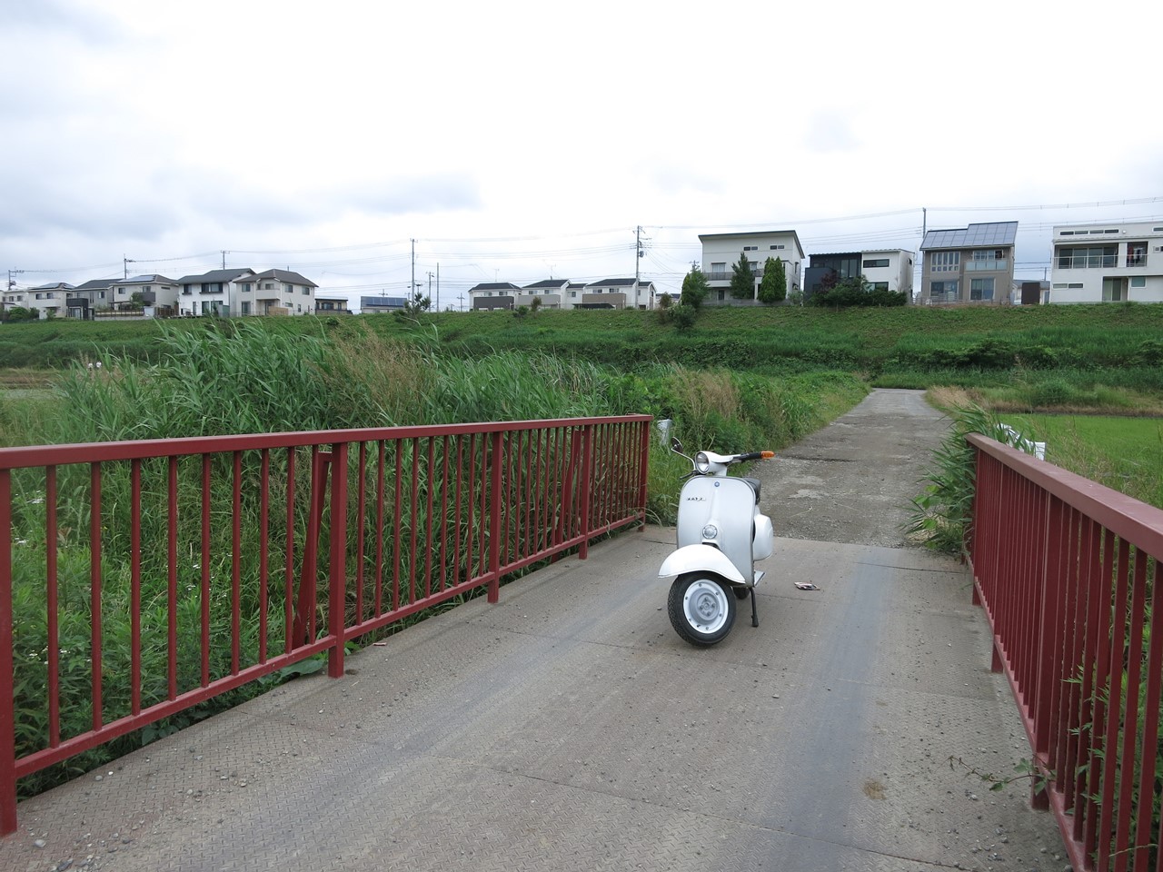 川沿いの赤い橋に停めた白いベスパ100の試運転風景
